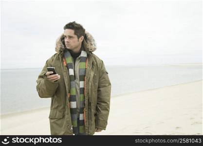 Mature man holding a mobile phone on the beach