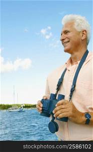 Mature man holding a pair of binoculars and smiling