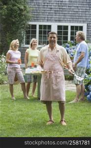 Mature man holding a serving dish with his friends in the background