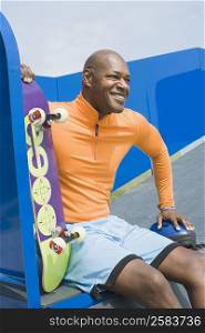 Mature man holding a skateboard and smiling