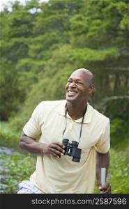 Mature man holding binoculars and smiling