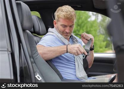 mature man in his car fastening his seatbelt