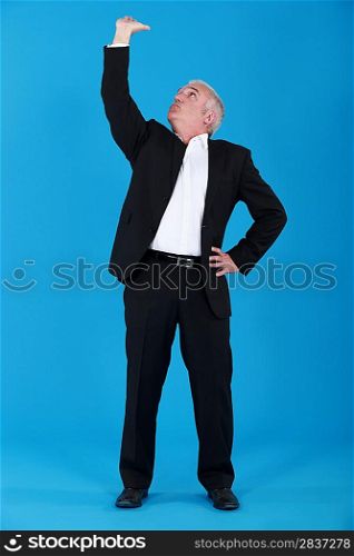 mature man in suit touching ceiling against blue background