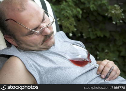 Mature man in the garden having fallen asleep from drinking too much