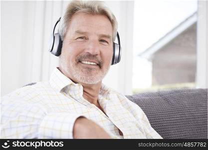Mature Man Listening To Music On Wireless Headphones