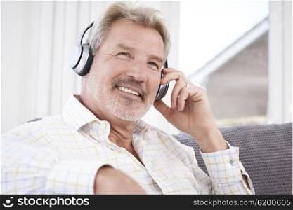 Mature Man Listening To Music On Wireless Headphones