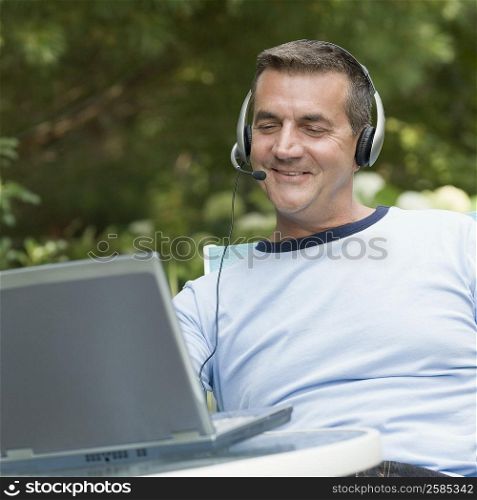Mature man looking at a laptop and wearing a headset