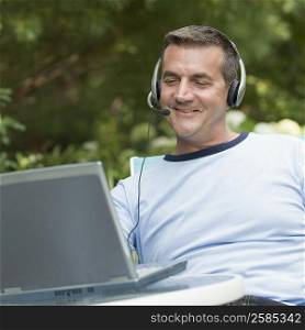 Mature man looking at a laptop and wearing a headset