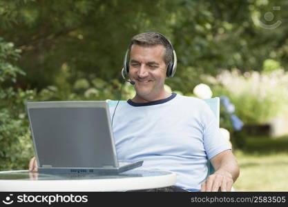 Mature man looking at a laptop and wearing headset