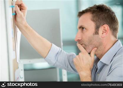 mature man looking at a wall planner in an office