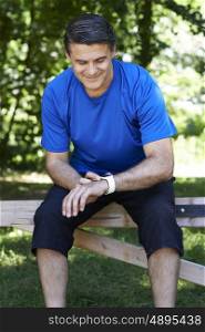 Mature Man Looking At Activity Tracker Whilst Exercising In Countryside