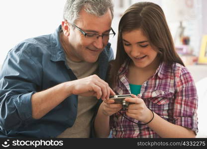 Mature man looking at digital camera with daughter
