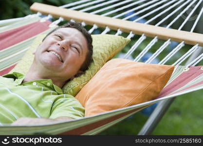 Mature man lying on a hammock and smiling