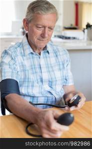 Mature Man Measuring Blood Pressure At Home