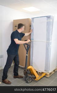 mature man moving huge cartons with trolley