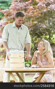 Mature man operating an ice cream maker with a mature woman looking at her and smiling