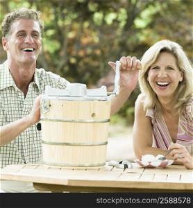 Mature man operating an ice cream maker with a mature woman sitting beside her