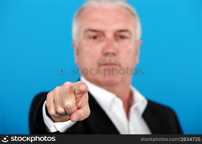 mature man pointing at something or someone isolated on blue