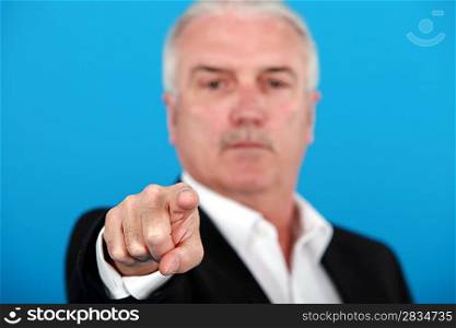 mature man pointing at something or someone isolated on blue