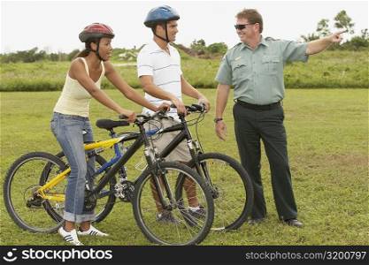 Mature man pointing forward with a mid adult man and a young woman