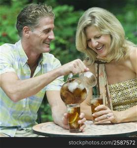 Mature man pouring ice tea into the glass of a mature woman
