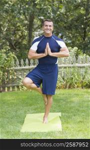 Mature man practicing yoga in a tree pose