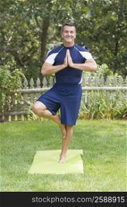 Mature man practicing yoga in a tree pose