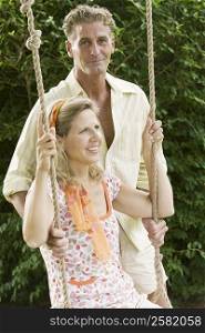 Mature man pushing a mature woman on a rope swing