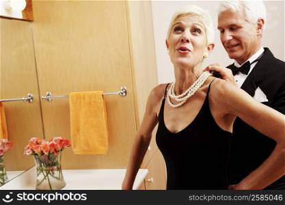Mature man putting a pearl necklace around a senior woman&acute;s neck