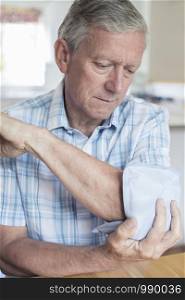 Mature Man Putting Ice Pack On Painful Elbow