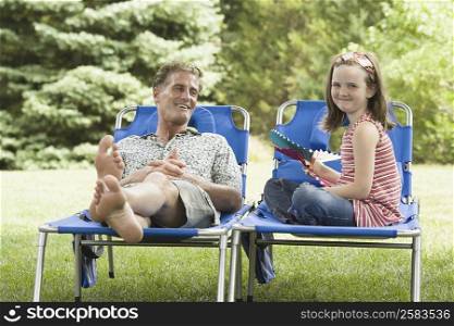 Mature man reclining on a lounge chair beside his daughter