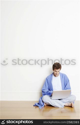 Mature man sitting cross-legged on the floor and using a laptop