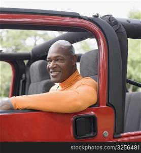 Mature man sitting in a jeep and smiling