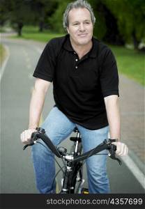 Mature man sitting on a bicycle and smiling