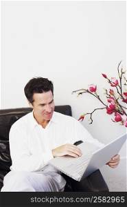 Mature man sitting on a couch and using a laptop