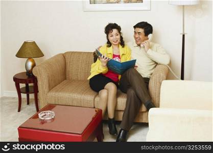 Mature man sitting on a couch with a mature woman talking on the telephone
