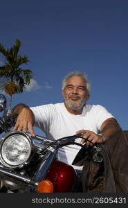 Mature man sitting on a motorcycle and grinning