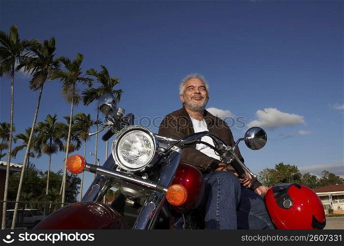 Mature man sitting on a motorcycle and smiling
