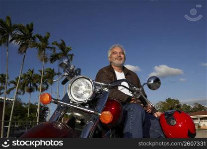 Mature man sitting on a motorcycle and smiling