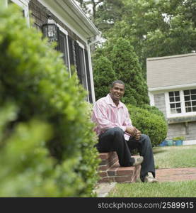 Mature man sitting on steps of a house