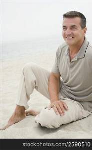 Mature man sitting on the beach and smiling