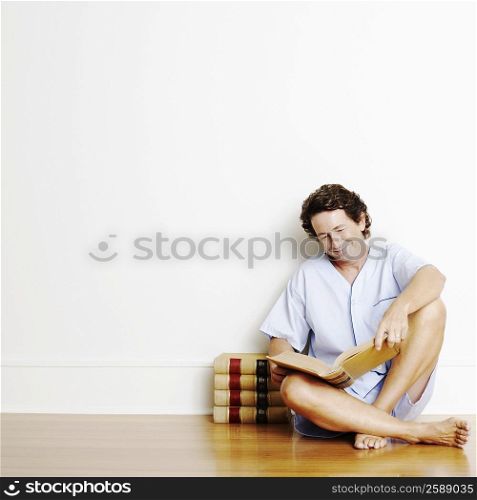 Mature man sitting on the floor and reading a book