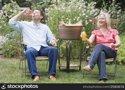 Mature man sitting with a mid adult woman and drinking cold drink