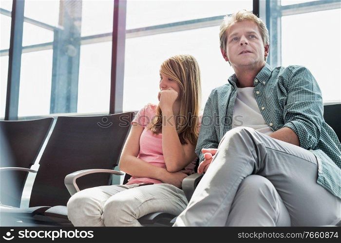 Mature man sitting with his daughter while waiting for their flight in airport