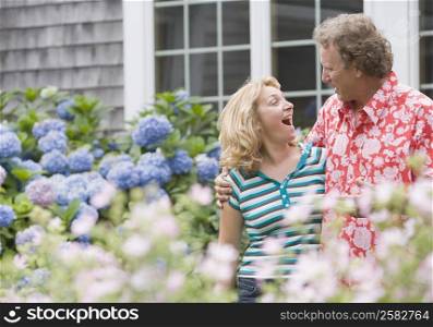Mature man standing arm around a mature woman in a garden