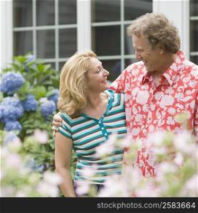 Mature man standing arm around a mature woman in a garden