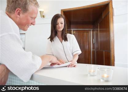 Mature man standing at a spa reception deciding on a treatment
