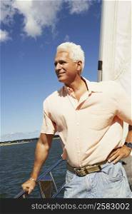 Mature man standing in a sailboat and smiling