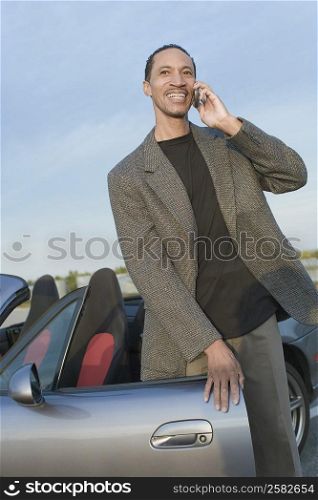 Mature man standing near a car and talking on a mobile phone