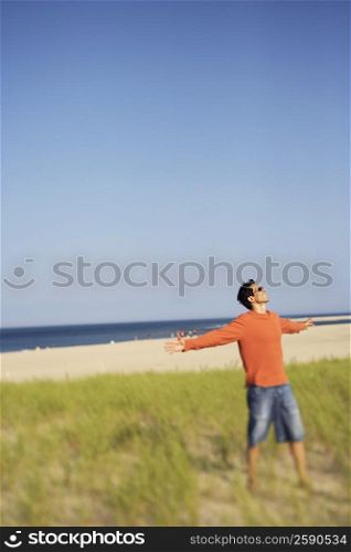 Mature man standing on the beach with his arms outstretched